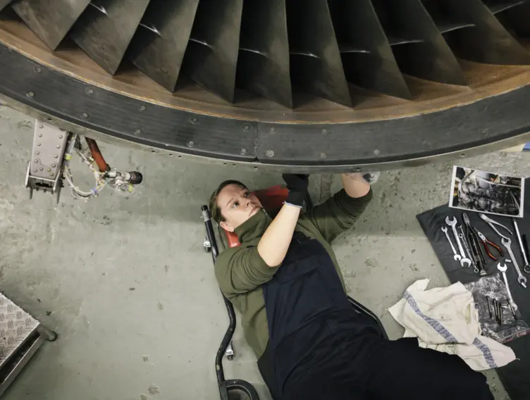 Handwerkerin liegt unter einer Turbine zur Reperatur.