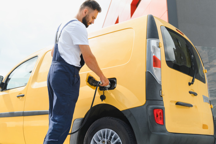 Mann tankt sein Auto mit Strom auf. 
