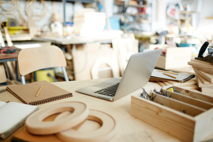 Schreibtisch in einem Atelier mit aufgeklapptem Laptop. 