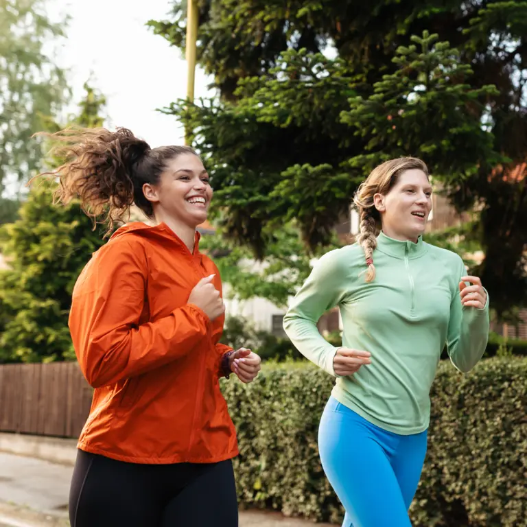 Zwei Frauen joggen an einem Vorgarten vorbei.