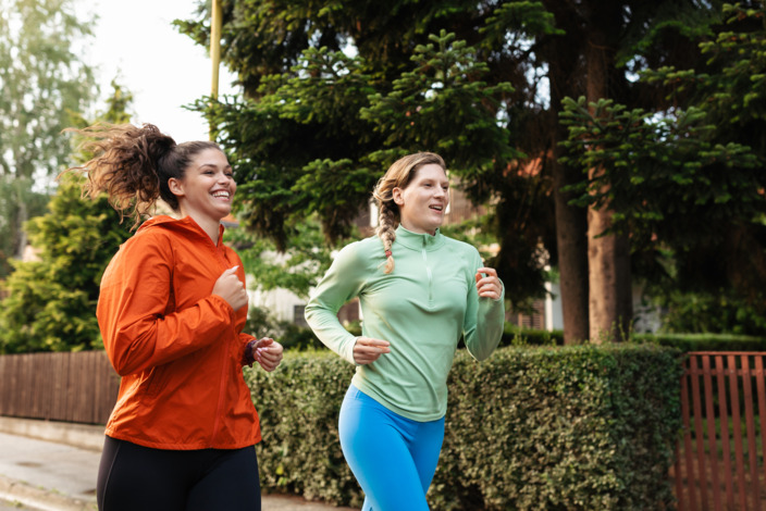 Zwei Frauen joggen an einem Vorgarten vorbei. 