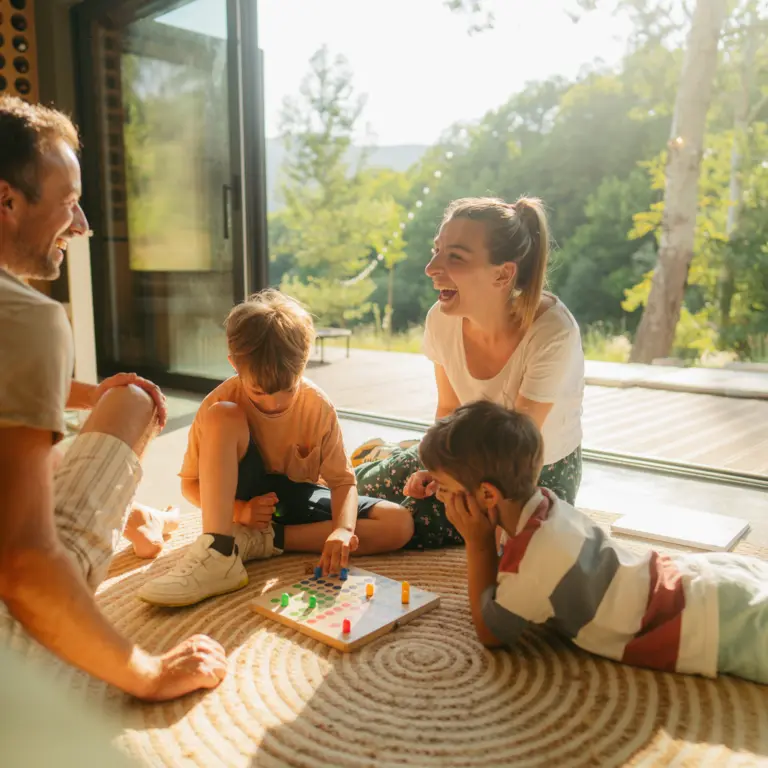 Eine Familie sitzt spielend auf dem Teppich.