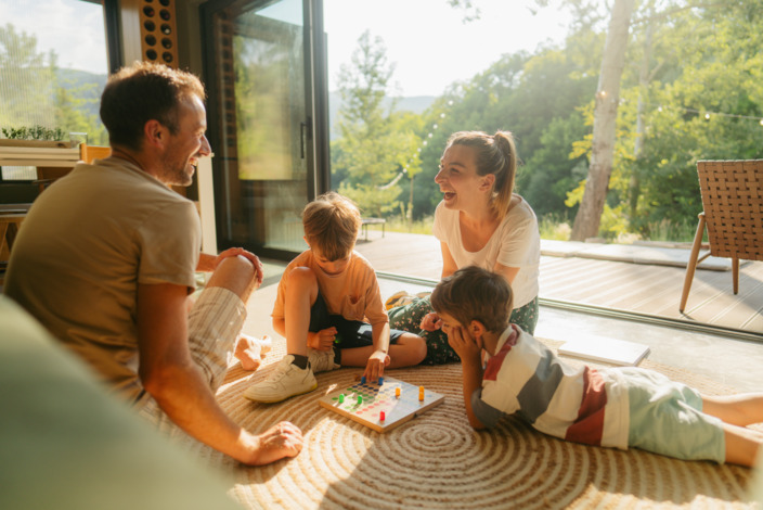 Eine Familie spielt zusammen im Wohnzimmer. 