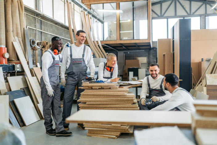 Gruppe von Handwerkern unterhalten sich in der Werkstatt.