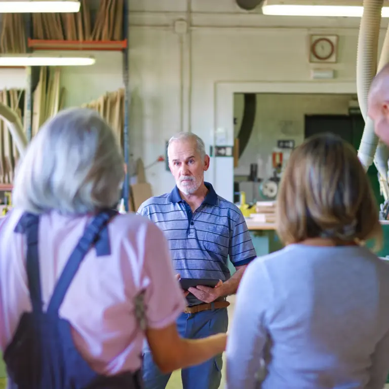Mitarbeiter im Handwerk versammeln sich um den Chef für eine Besprechung.