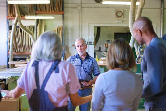 Mitarbeiter im Handwerk versammeln sich um den Chef für eine Besprechung.