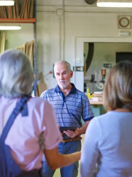 Mitarbeiter im Handwerk versammeln sich um den Chef für eine Besprechung.