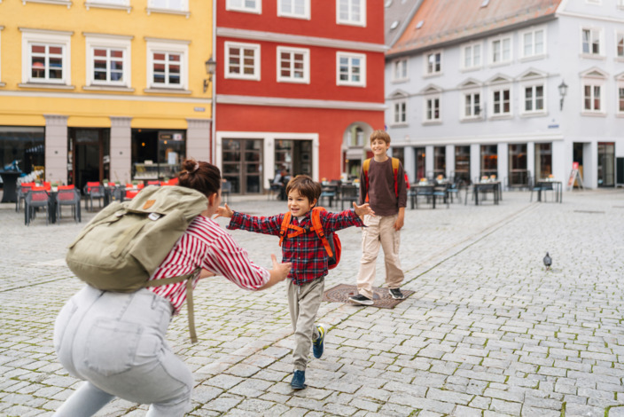 Erstklässler läuft nach Schulschluss in die geöffneten Arme seiner Mutter