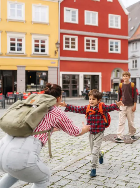Kinder kommen von der Schule und werden von ihrer Mutter begrüßt.