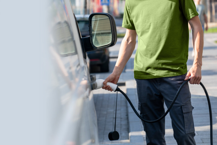 Mann lädt sein E-Auto an einer Stromtankstelle.