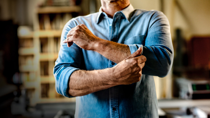 Handwerker krempelt sich die Hemdärmel hoch