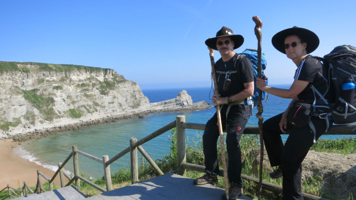 Willi und Ute Lethert sitzen auf dem Geländer einer Treppe, die hinunter zu einem Strand führt.