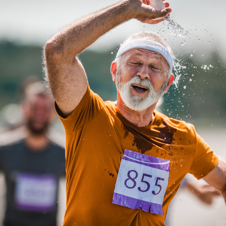 Marathon-Läufer schüttet sich während eines Wettkampfs Wasser über den Kopf