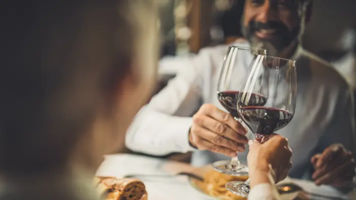 Eine Frau und ein Mann stoßen im Restaurant mit einem Glas Wein an