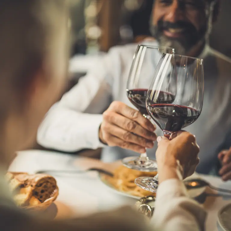 Paar stößt beim Restaurantbesuch mit zwei Gläsern Rotwein an