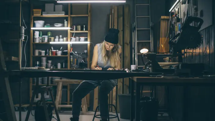Handwerkerin sitzt am späten Abend noch am Tisch und arbeitet.
