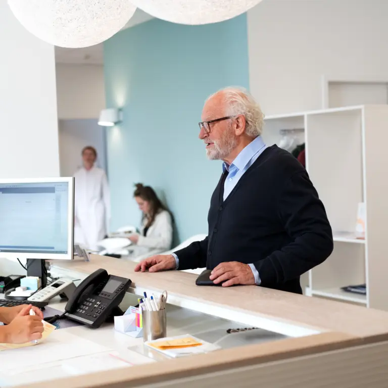 Mann steht am Empfang einer Arztpraxis