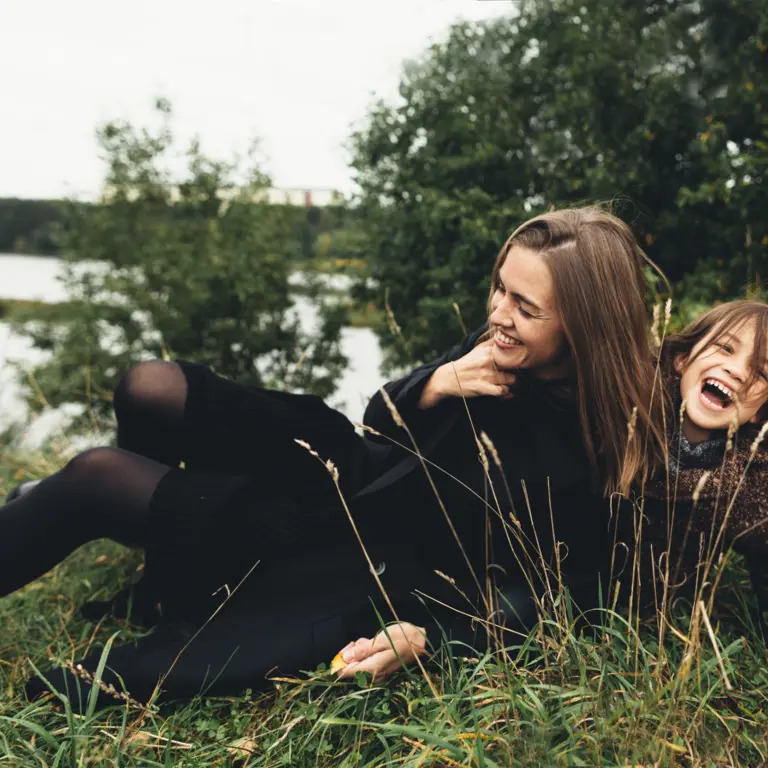 Mutter und Tochter tollen am Ufer eines Sees herum