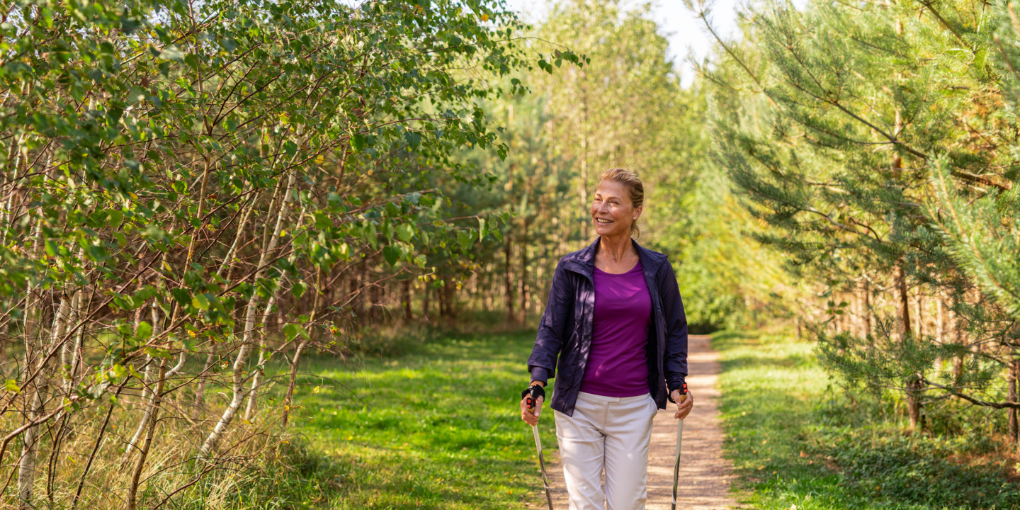 Frau beim Nordic Walking durch den Wald