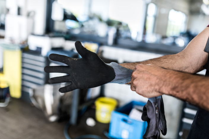 Handwerker zieht einen Arbeitshandschuh an