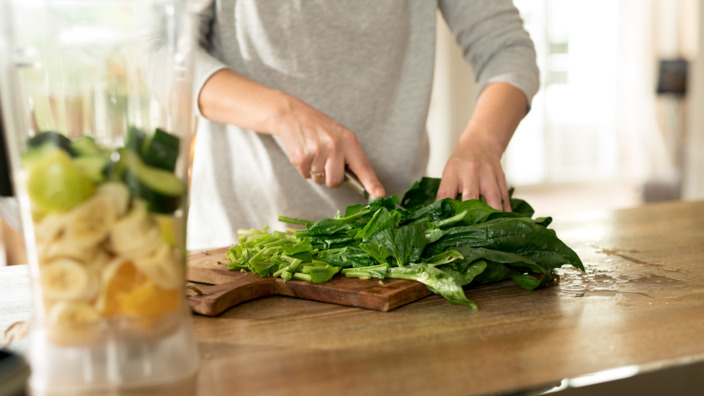 Frau schneidet in der Küche grünes Gemüse