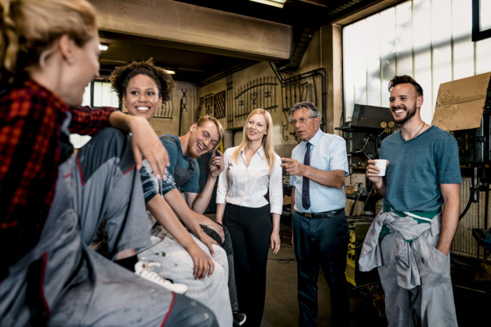 Kollegen aus Büro und Werkstatt stehen während einer Kaffeepause beieinander