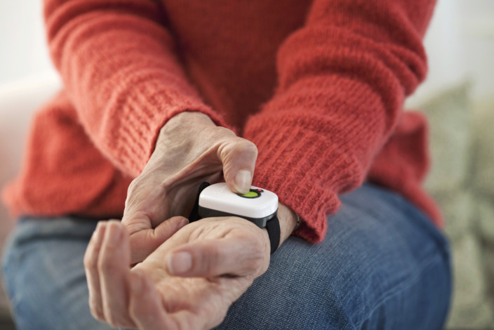 Ältere Person betätigt Alarmknopf am Handgelenk