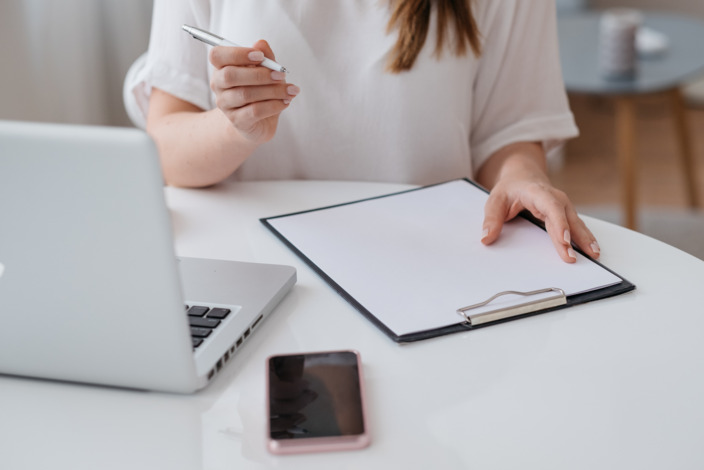 junge Frau recherchiert am Laptop und macht sich Notizen