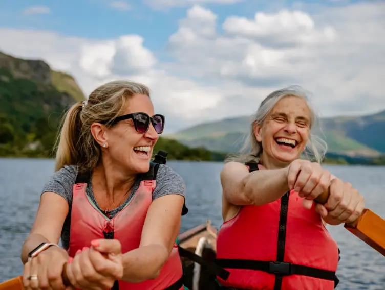 Zwei ältere Frauen fahren mit einem Kanu auf einem See.