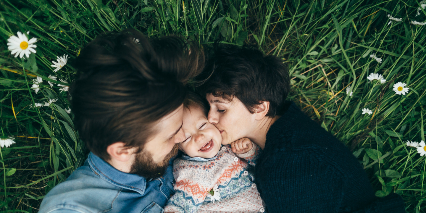 Mutter, Vater und Kind liegen glücklich auf einer Wiese