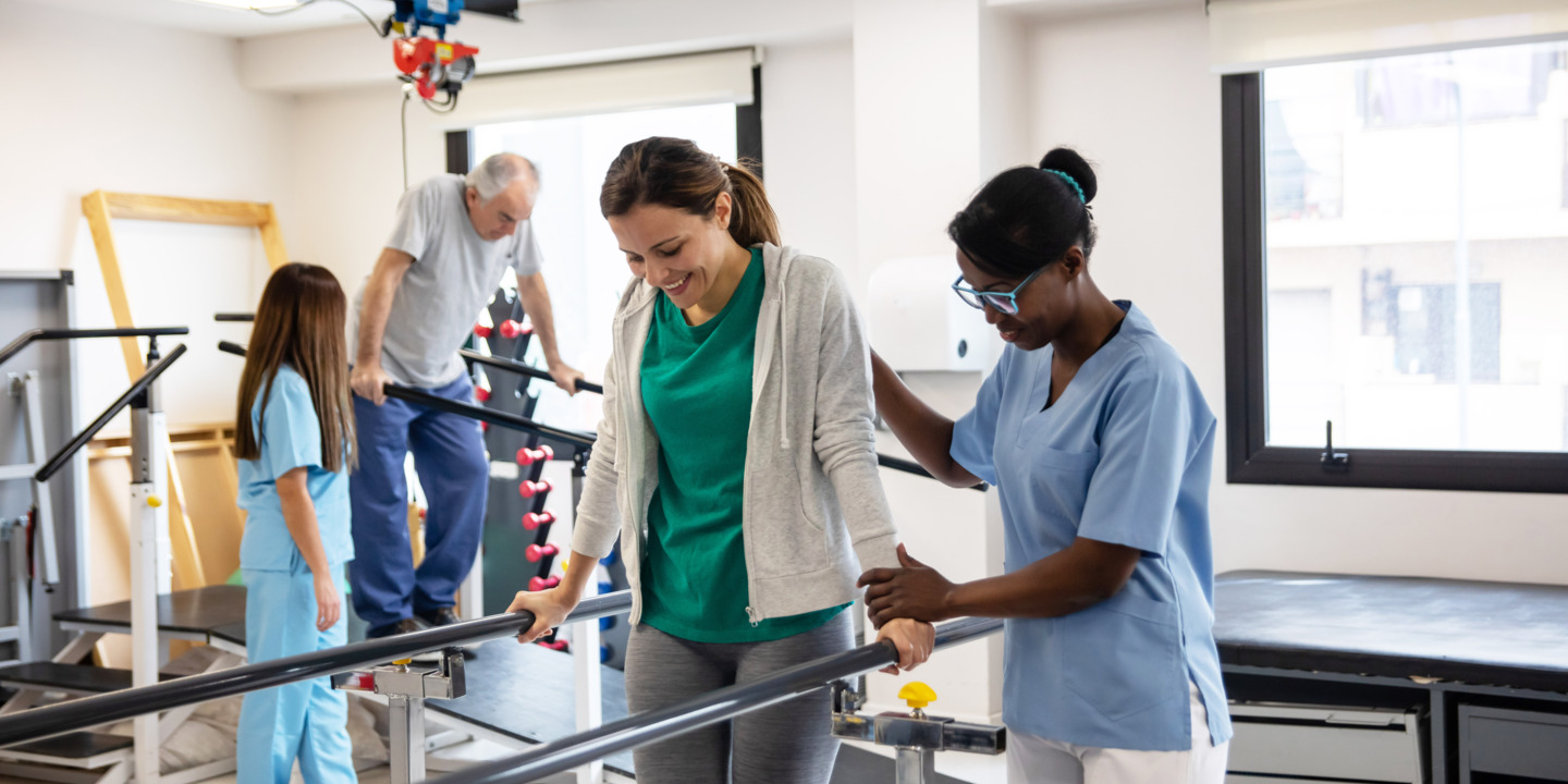 Reha-Patienten lernt mit einer Physiotherapeutin wieder zu laufen