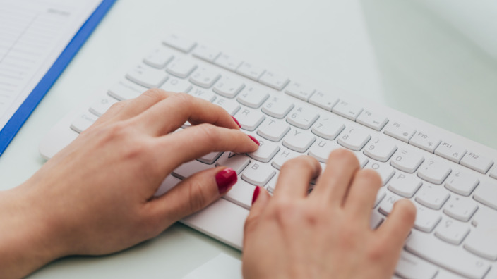 Hände einer Frau tippen auf eine Computertastatur