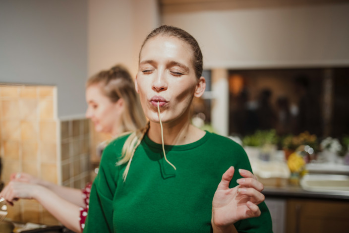 junge Frau saugt genüsslich eine Spaghetti in ihren Mund