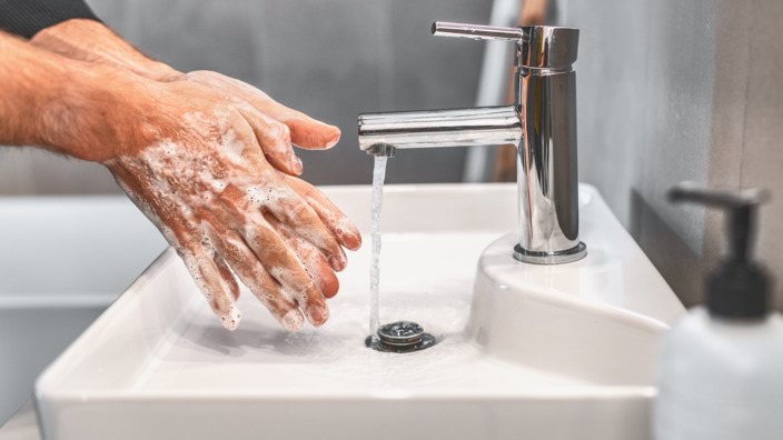 eingeseifte Hände und ein laufender Wasserhahn