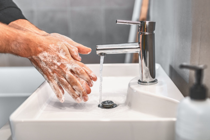 eingeseifte Hände unter einem laufenden Wasserhahn