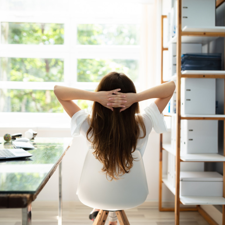 Frau sitzt im Büro auf Stuhl und entspannt sich