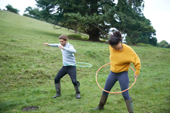 Mann und Frau benutzen Hoola Hoop Reifen.