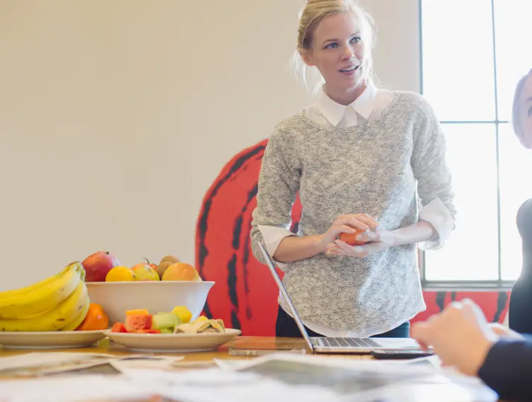 Kolleginnen unterhalten sich im Pausenraum, bei ihnen steht eine Schale mit Obst.