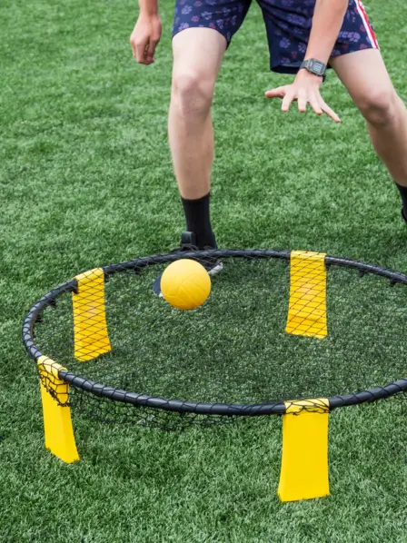 Person spielt Spikeball auf dem Rasen