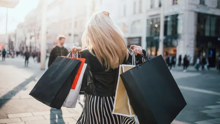 Frau mit vielen Einkaufstüten geht in der Stadt shoppen.