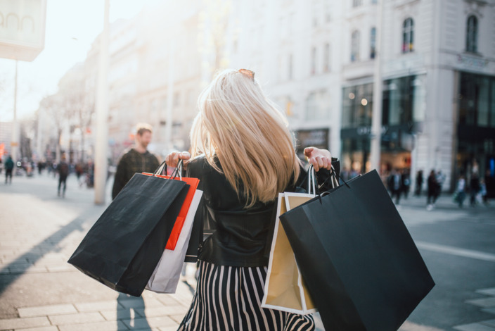 Frau mit vielen Einkaufstüten geht in der Stadt shoppen.
