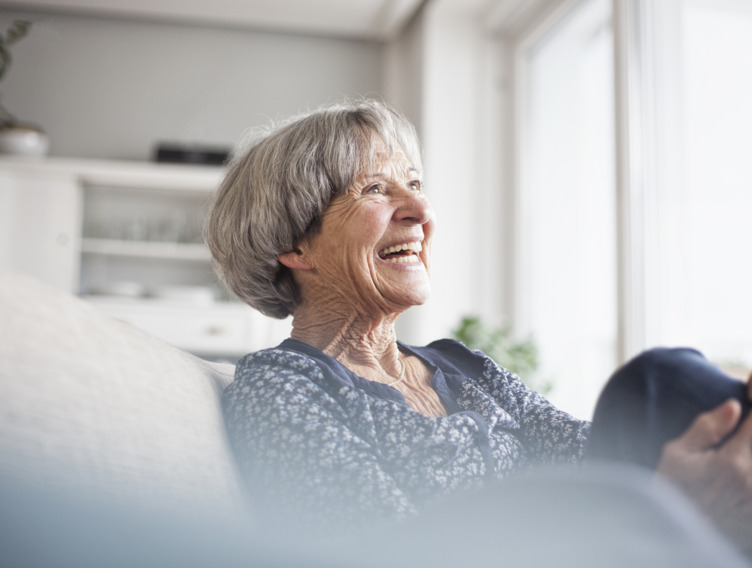 Seniorin sitzt gut gelaunt auf ihrer Couch