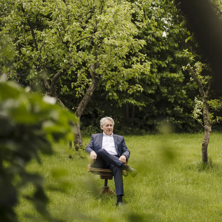 Mann sitz auf einem Stuhl auf einer Wiese