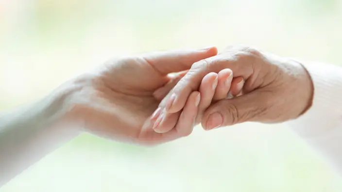 junge Frau hält die Hand einer alten Frau