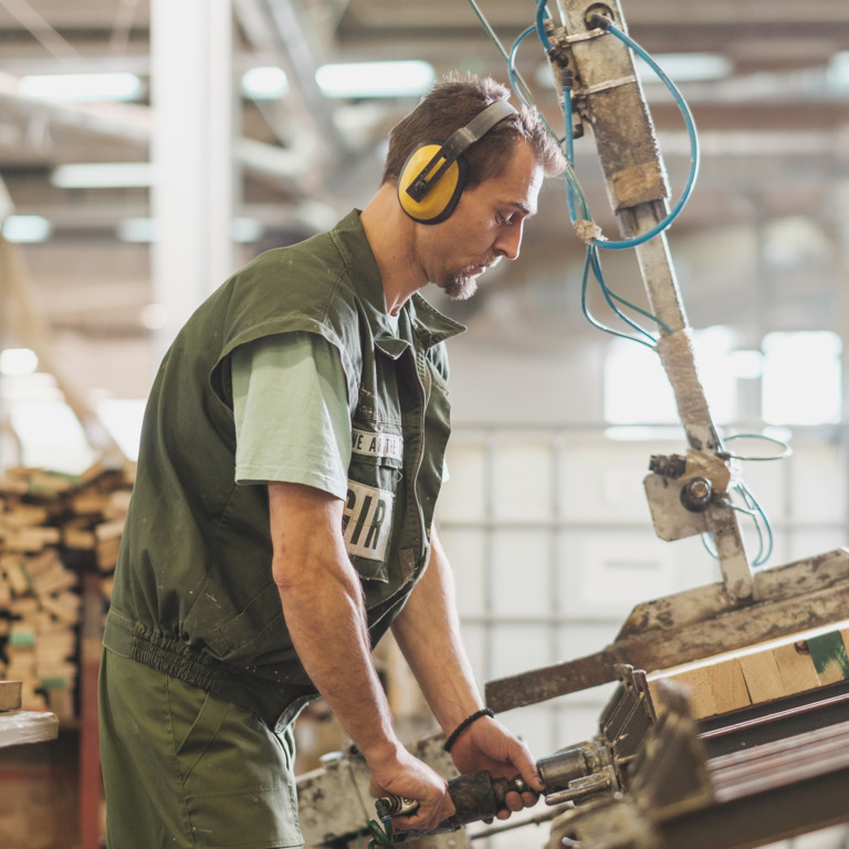 Tischler arbeitet mit Gehörschutz an einer Säge