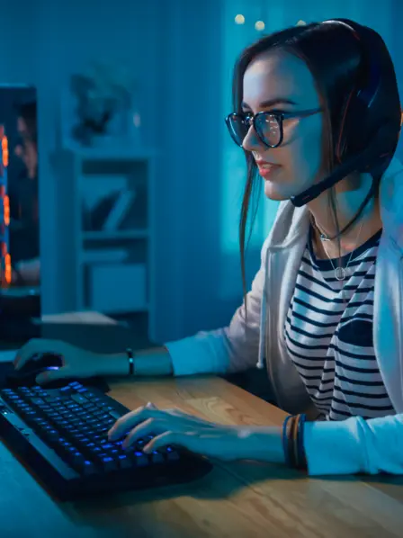 Junge Frau sitzt am Schreibtisch und spielt Computerspiele.