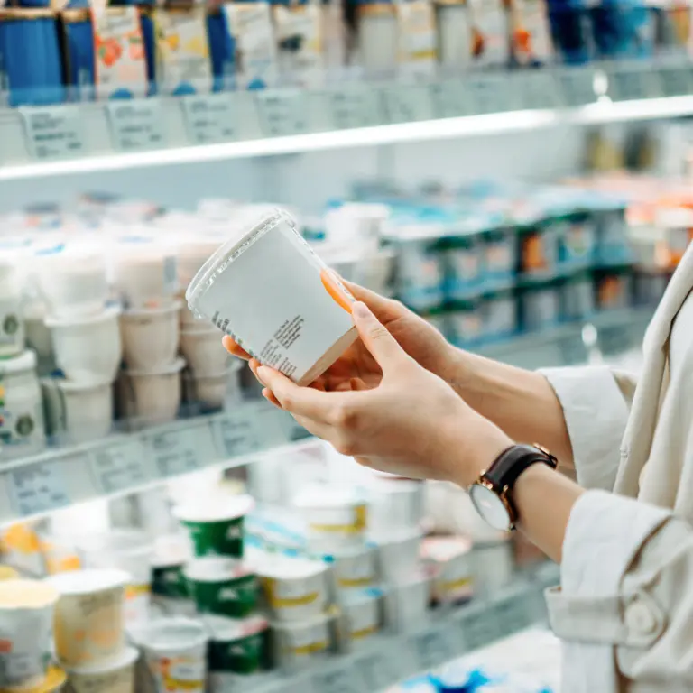 Frau hält ein Produkt aus dem Kühlregal in der Hand
