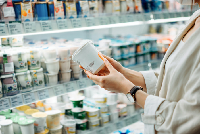 Frau hält ein Produkt aus dem Kühlregal in der Hand