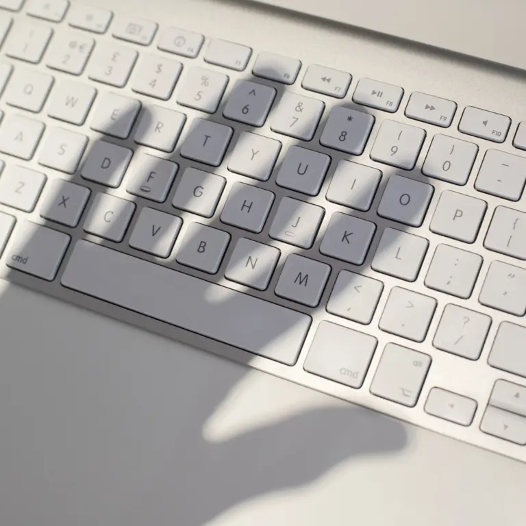 Schatten einer Hand über einer Computertastatur.