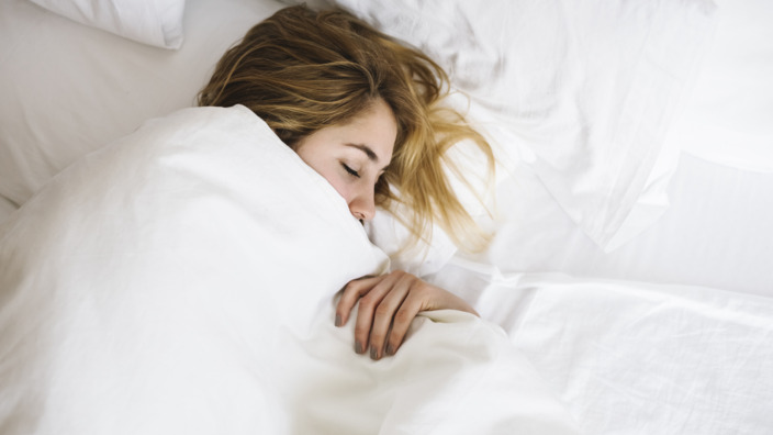 Frau liegt schlafend im Bett.